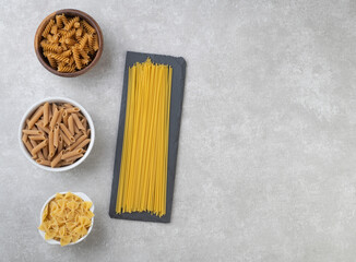 Assorted pasta over concrete countertop with copy space