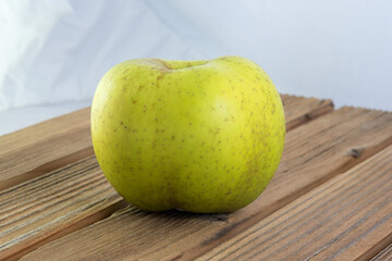 una mela dal colore verde chiaro su una tavola di legno, i frutti stagonali e la loro importanza nelle diete