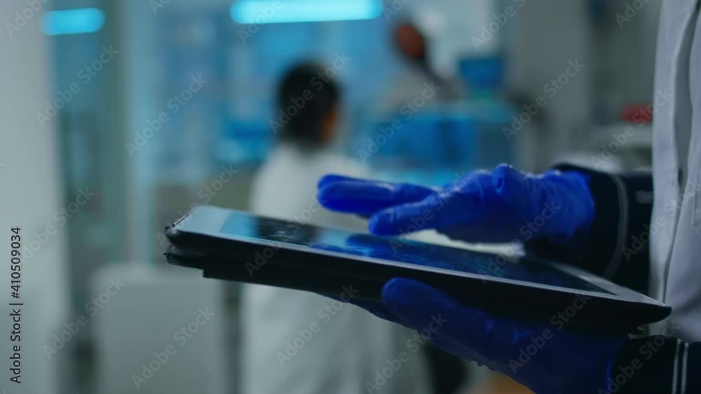 Aufkleber close up of scientist examining datas from tablet while team of biologists doing biological research