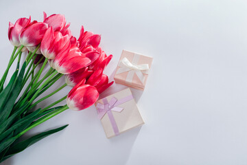 Bouquet of pink tulips with gift voxes on white background. Flowers for Valentines day as present.