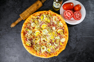 Pizza deliciosa com ingredientes na mesa de madeira com fundo escuro.