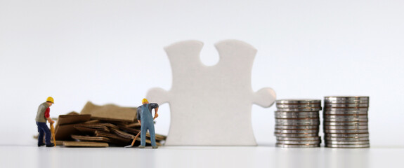 Miniature people and business concept. A piece of puzzle between a pile of paper and a pile of...