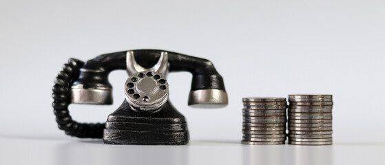 Miniature phone and coins on background.
