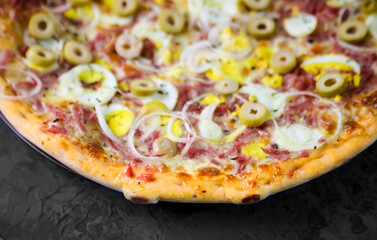 Pizza deliciosa com ingredientes na mesa de madeira com fundo escuro.