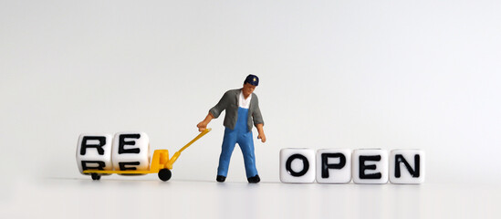 A miniature man carrying RE on a cart. The concept of reopening.
