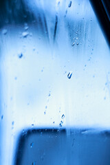 Fototapeta na wymiar Raindrops on the glass of the car in cold colors