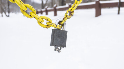 Fototapeta na wymiar Padlock On A Yellow Chain in the Snow