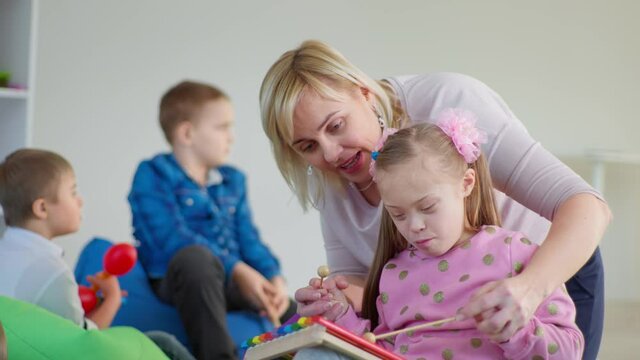 teacher teaches a girl with a disability to play the xylophone during a music lesson, entertainment for children with down syndrome