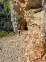 Obraz premium Cain, Spain - September 1, 2020: Female hiking trough the Cares Route in the heart of Picos de Europa National Park, Spain. Narrow and impressive canyon between cliffs, bridges and footpaths.