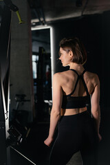 Fototapeta na wymiar Portrait of Confident Brunette Woman Wearing Performance Wear in Gym