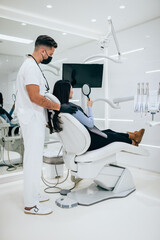 Beautiful young woman sitting on dental chair and having dental treatment.