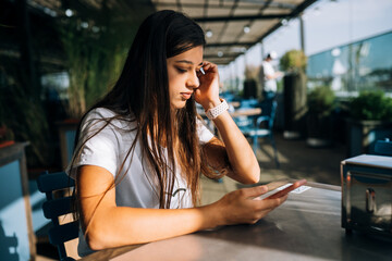 Young woman in a cafe holding a smartphone in her hands