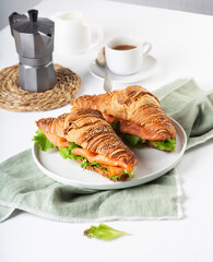 Croissant Sandwich with salmon and salad leaves on the table