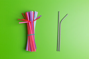 Stainless steel reusable drinking straw with many multicolored plastic straws on yellow background. Zero waste concept.