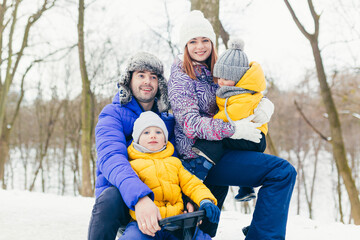Happy family walking in winter park together, two adult man and woman and two children