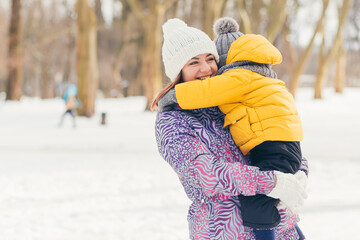 Woman mother walks and relaxes with her little sons, in winter park, having fun