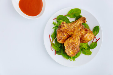 Fried chicken drumsticks with spicy sauce on white background.