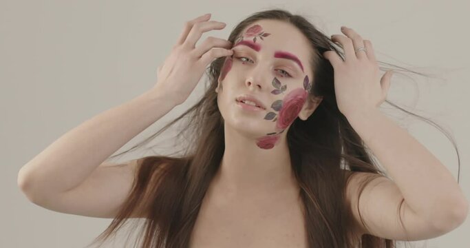 girl with fragile bare shoulders and beautiful long hair elegantly poses for the camera touching her face