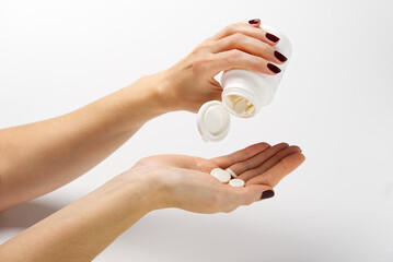 woman hand holding plastic jar with white pills, taking vitamins minerals drugs