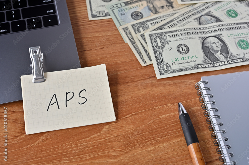 Poster on the desk there are bills, a keyboard, and memos with the word aps written on it. it was an abbrev