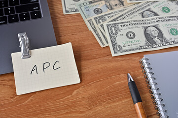 On the desk there are bills, a keyboard, and memos with the word APC written on it. It was an abbreviation for the financial term average propensity to consume.