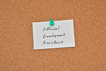 There's a clipboard, a pen and a notebook with a sticky note stuck to it that says Official Development Assistance.