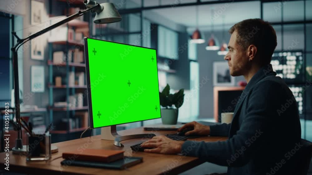 Poster Handsome Caucasian Specialist Working on Desktop Computer with Green Screen Mock Up Display at Home Living Room. Freelance Man Chatting to Clients Over the Internet on Social Networks.
