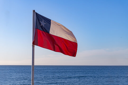 Chilean flag with pacific ocean and blue sky at behind
