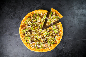 Pizza deliciosa com ingredientes na mesa de madeira com fundo escuro.