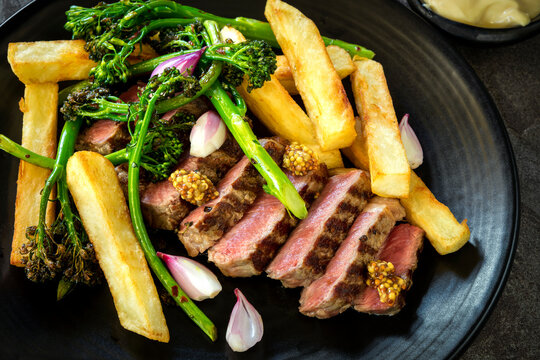 Grilled porterhouse steak with broccolini shallots french fries and mustard