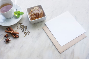 A cup of green tea with flavouring spices of cinnamon, peppermint, honey and anise and blank card for copy space.