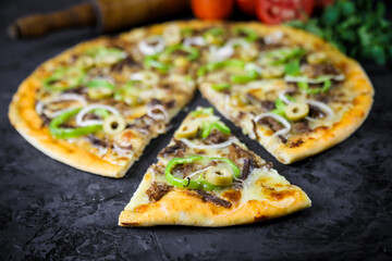 Pizza deliciosa com ingredientes na mesa de madeira com fundo escuro.