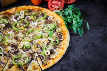 Pizza deliciosa com ingredientes na mesa de madeira com fundo escuro.