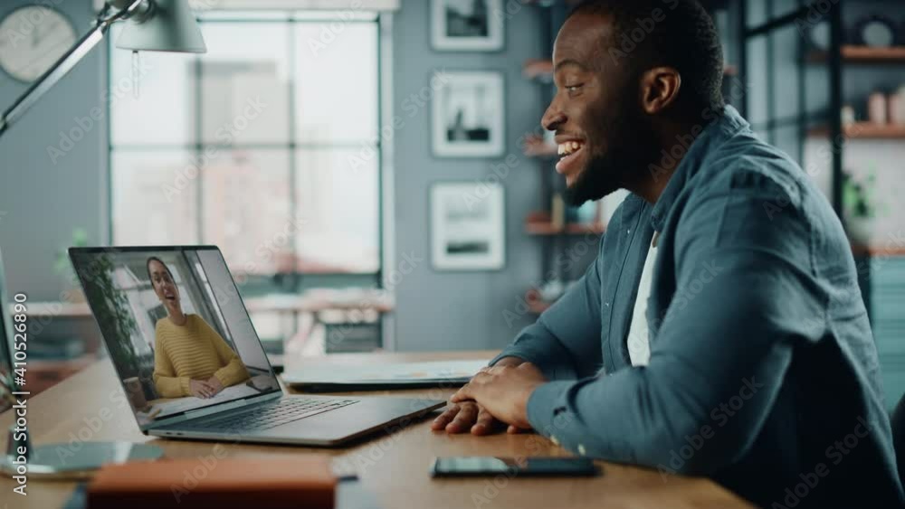 Poster handsome african american man having a video call on laptop computer while sitting behind desk in li