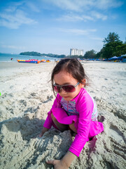 Little asian girl playing on the beach. Vacation and relaxing concept.