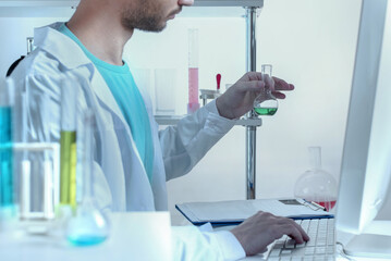 Cropped view A chemistry lab technician in protective goggles and a mask examines an experimental...