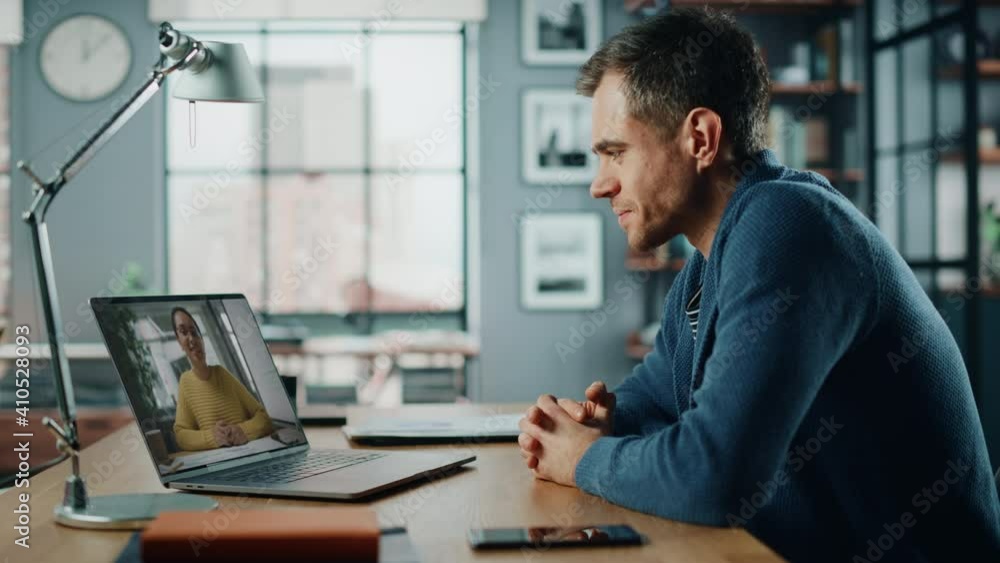 Aufkleber Handsome Caucasian Man Having a Video Call on Laptop Computer while Sitting Behind Desk in Living Room. Freelancer Working From Home and Talking to Colleagues and Clients Over the Internet.