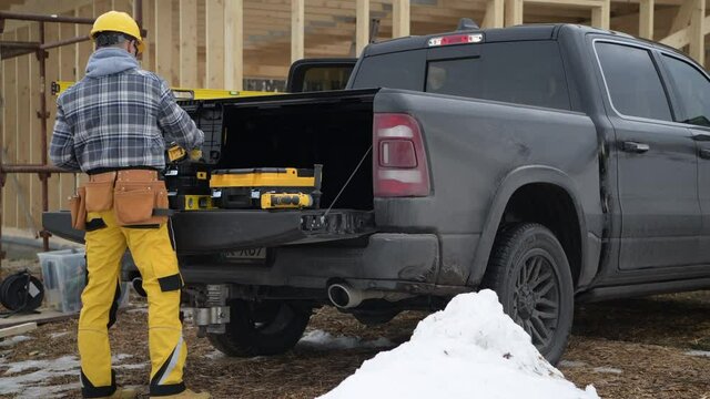 Construction Contractor and His Day Job in the Construction Zone. Selecting Powertools on His Pickup Truck Bed