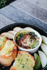 Baked spinach with cheese and garlic bread on wooden table - Italian food style.
