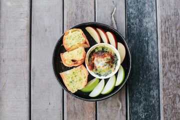Baked spinach with cheese and garlic bread on wooden table - Italian food style.