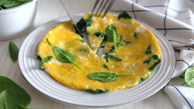 egg omelet with spinach and cheese on a white plate. High quality FullHD footage