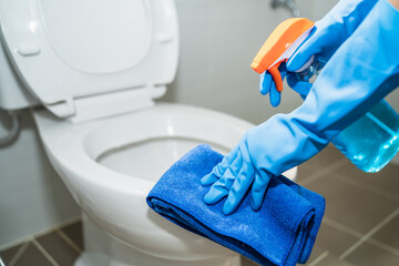 close up hands women wearing protect glove blue using liquid cleaning solution cleaning flush toilet, disinfection and hygiene concept