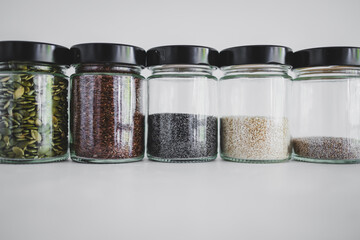 seed jars with sesame poppy pupmkin chia and flax seeds as important nutrient sources for nutrition shot on white background