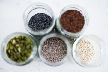 seed jars with sesame poppy pupmkin chia and flax seeds as important nutrient sources for nutrition shot on white background
