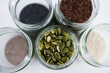 seed jars with sesame poppy pupmkin chia and flax seeds as important nutrient sources for nutrition shot on white background
