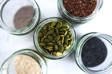 seed jars with sesame poppy pupmkin chia and flax seeds as important nutrient sources for nutrition shot on white background