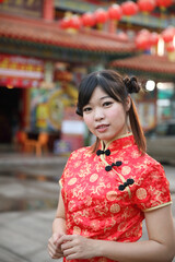 beauty woman wear red cheongsam looking and smile in chinese new year