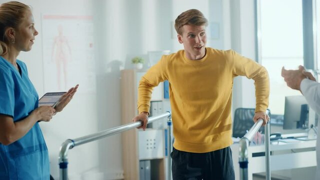 Hospital Physical Therapy: Portrait of Strong Male Patient with Injury Successfully Walks Holding Parallel Bars. Physiotherapist, Rehabilitation Doctor, Help, Assist, Disabled Person. Slow Motion