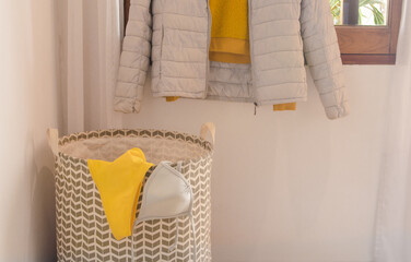 Part of hanged clothes and modern basket with a bikini in gray and yellow colors.