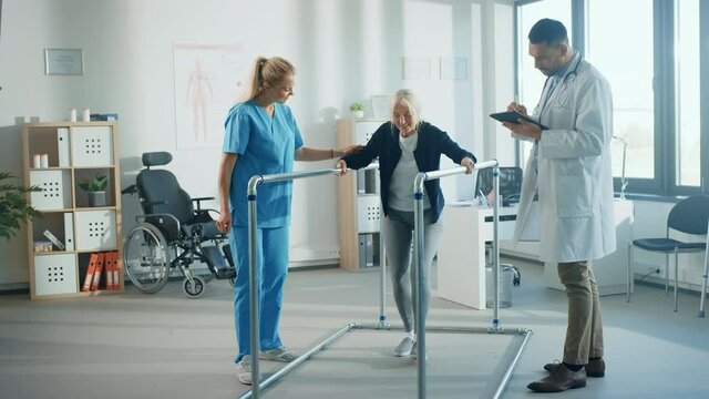 Hospital Physical Therapy: Portrait of Strong Senior Female Patient with Injury Successfully Walks Holding Parallel Bars. Physiotherapist, Rehabilitation Doctor, Help, Assist Disabled Patient